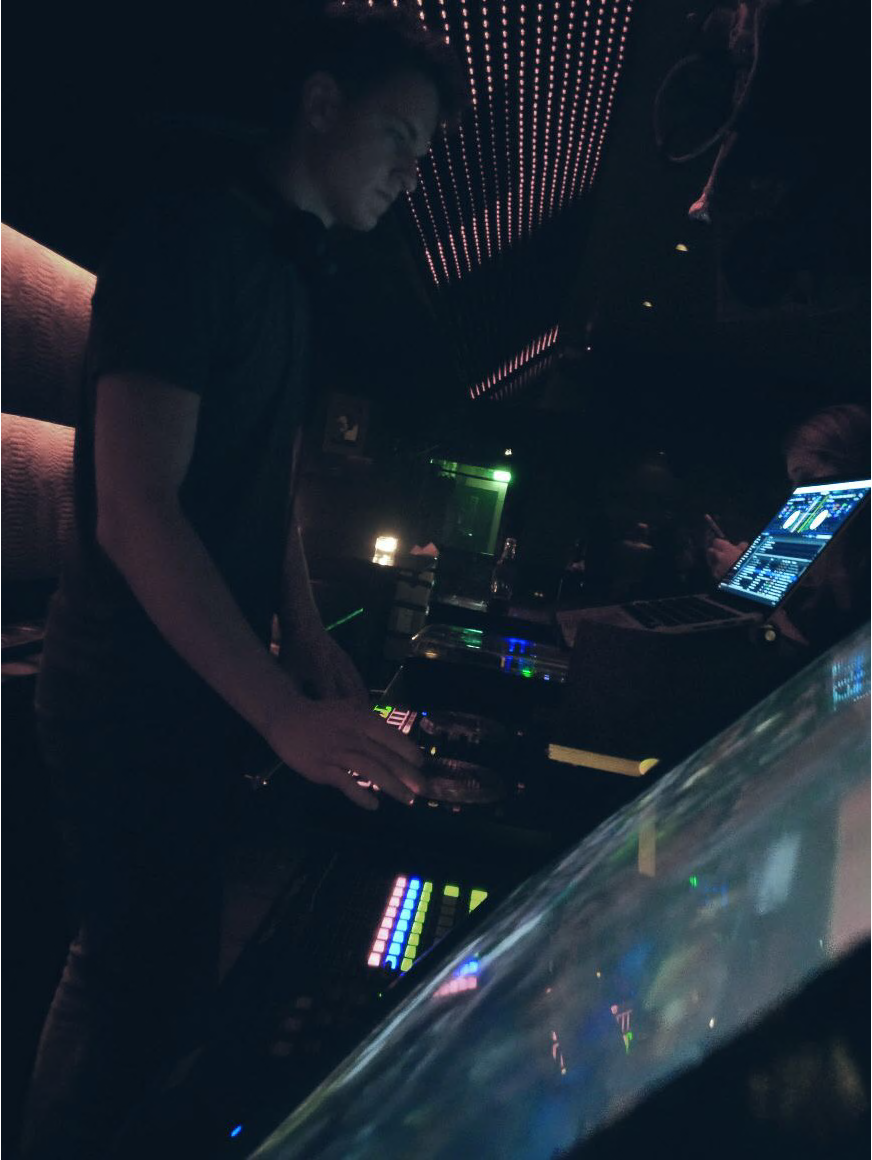 noelgon playing a late-night club set, dark stage lit by ambient red.